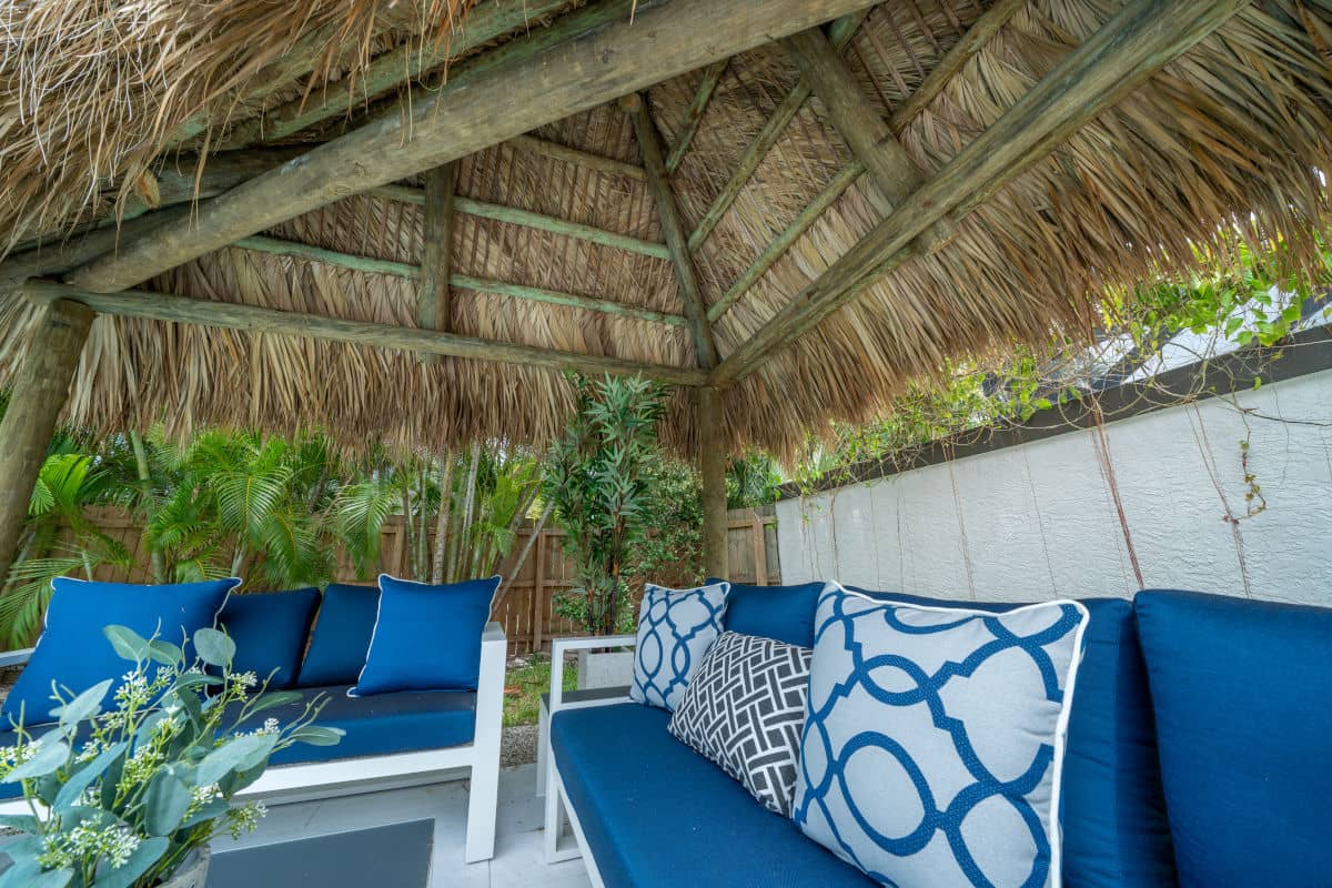 Triangular tiki roof built for a seating area in a backyard.