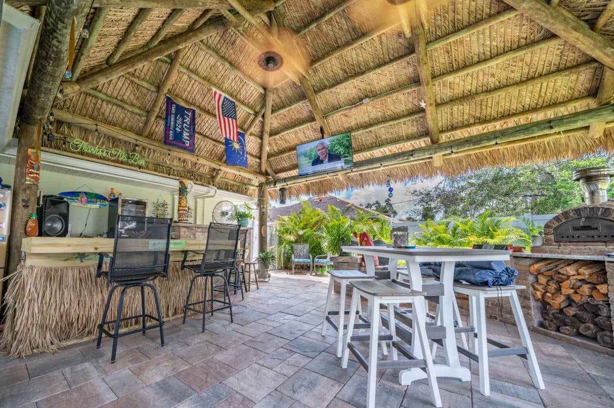 Back yard tiki with a bar and an outdoor kitchen area for entertaining guests.